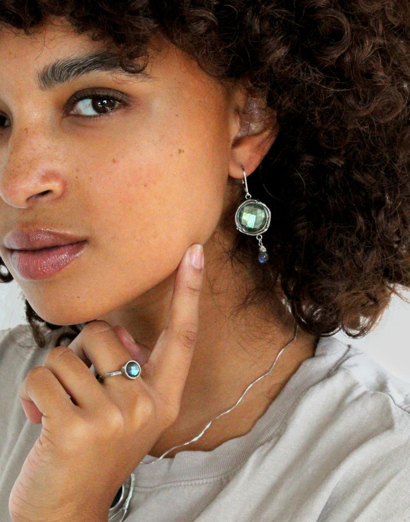 Model wearing hand-crafted sterling silver jewelry from the Haven Collection, including a green gemstone ring and matching earrings, showcasing elegant, nature-inspired designs.